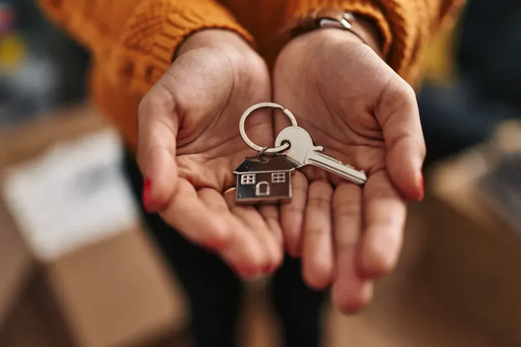 Close of hands holding a set of house keys with a house keychain